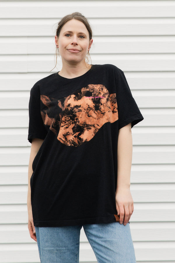 Person wearing a black t-shirt with a bleached ascent, upcycled in canada