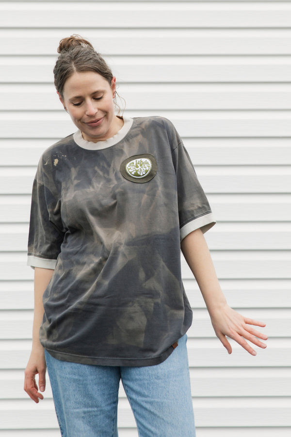 Person wearing a distressed t-shirt with a logo against a white background