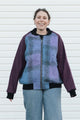 Person wearing a purple and blue plaid zip up jacket with plum sleeves, upcycled in canada