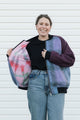 Person wearing a purple and blue plaid zip up jacket with plum sleeves, upcycled in canada