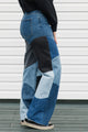 Person wearing patchwork jeans in front of a white wall.