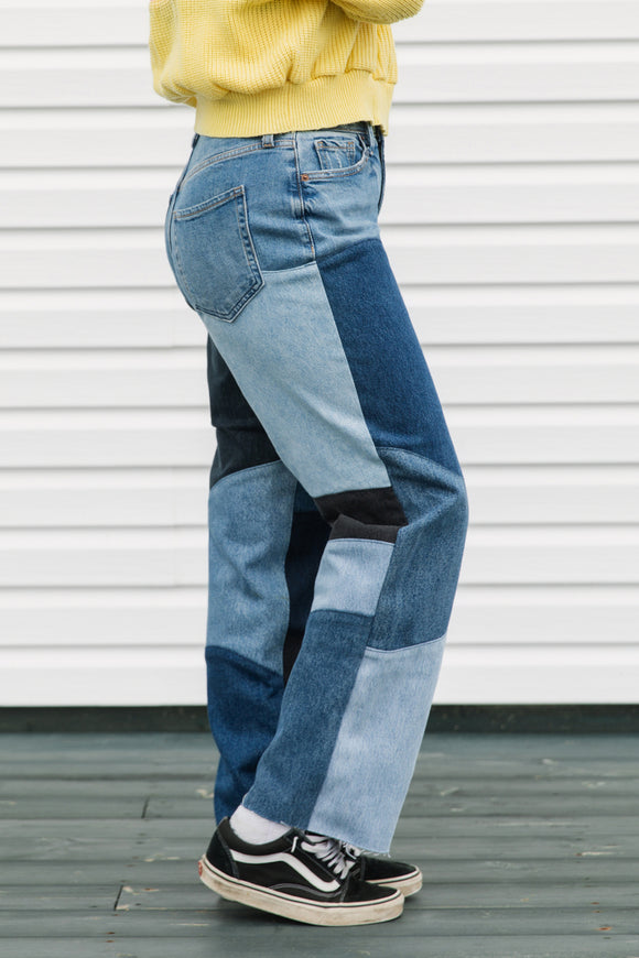 Person wearing patchwork jeans with a plain background