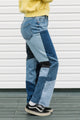 Person wearing patchwork jeans with a plain background