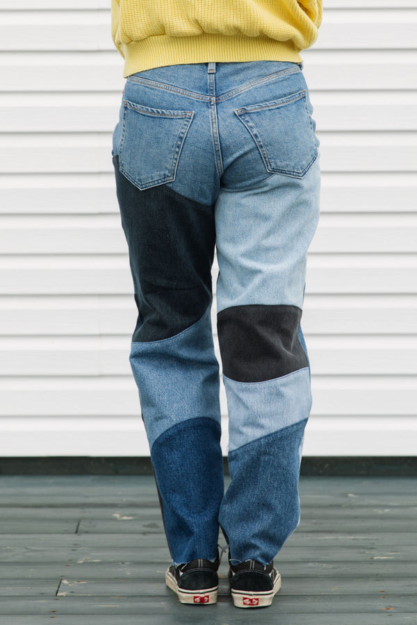 Person wearing patchwork jeans with a plain background