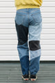 Person wearing patchwork jeans with a plain background
