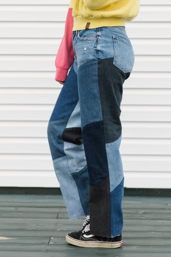 Person wearing patchwork jeans with a plain background