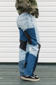 Person wearing patchwork jeans with a white wall background