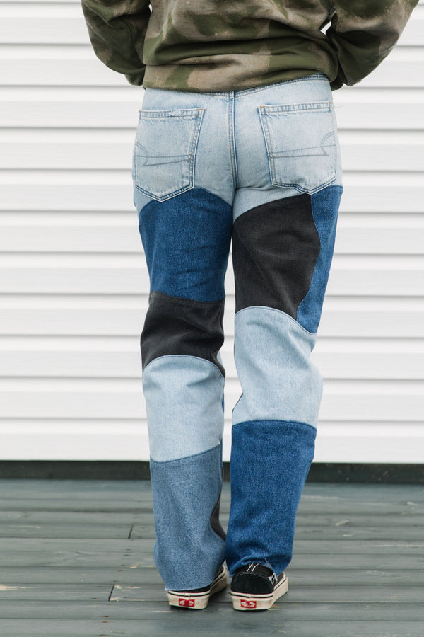 Person wearing patchwork jeans with a plain background