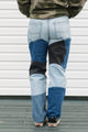 Person wearing patchwork jeans with a plain background