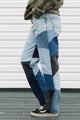 Person wearing patchwork jeans with a white wall background