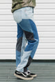 Person wearing patchwork jeans with a white background