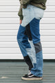 Person wearing patchwork jeans with a plain background