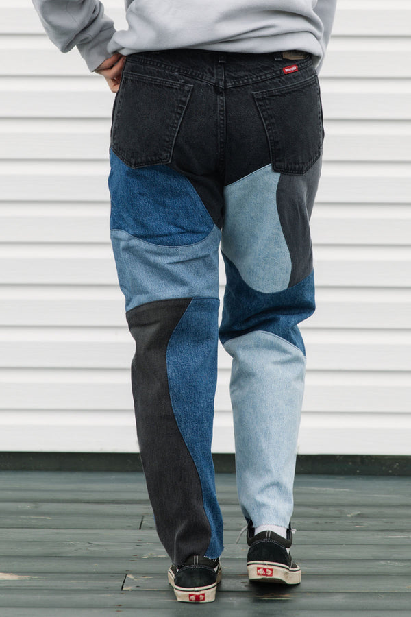 Person wearing patchwork jeans with a plain background