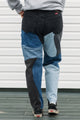 Person wearing patchwork jeans with a plain background