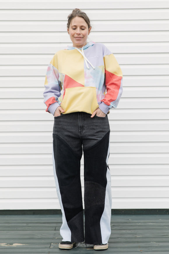 Person wearing a colorful sweater and black pants standing against a white background, upcycled in canada