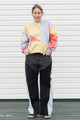 Person wearing a colorful sweater and black pants standing against a white background, upcycled in canada