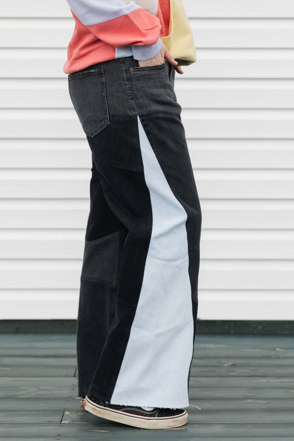 Person wearing a colorful sweater and black pants standing against a white background, upcycled in canada