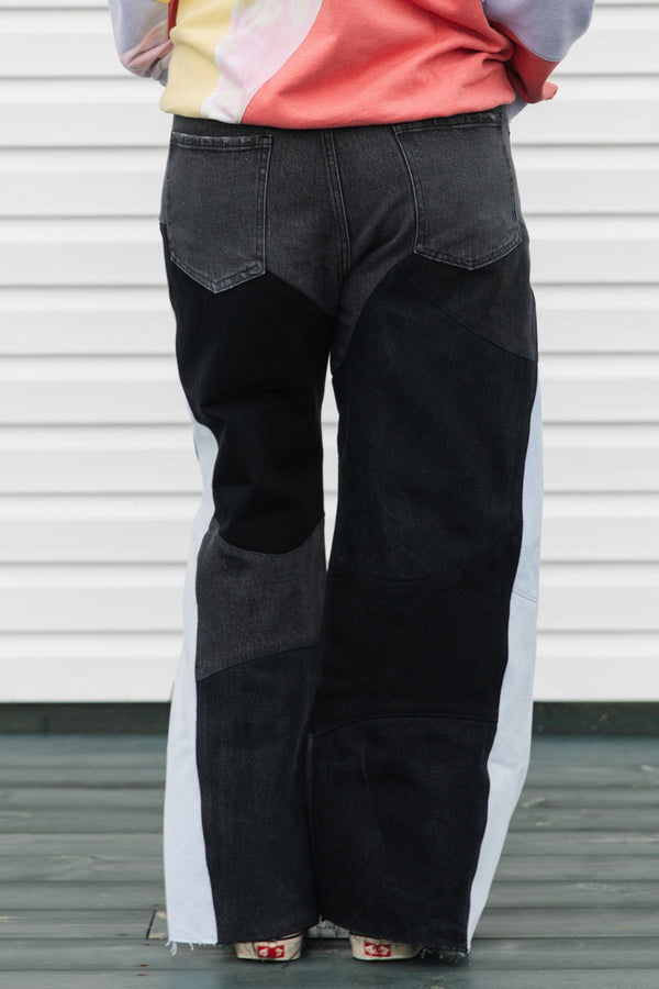 Person wearing a colorful sweater and black pants standing against a white background, upcycled in canada