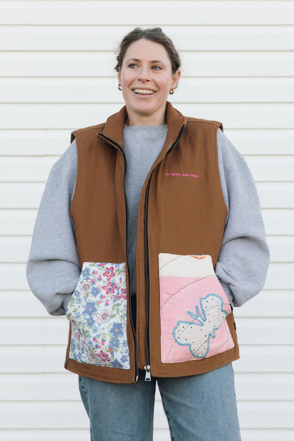 Woman wearing a brown quilted vest with floral and cartoon designs on a white background