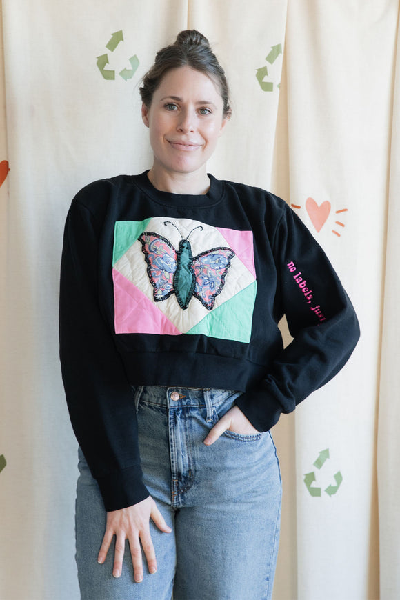 Person wearing a black sweatshirt with a colorful butterfly design, upcycled in canada