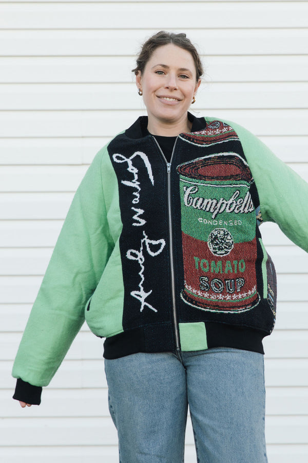 Person wearing a colorful jacket with Campbell's Tomato Soup design against a white background