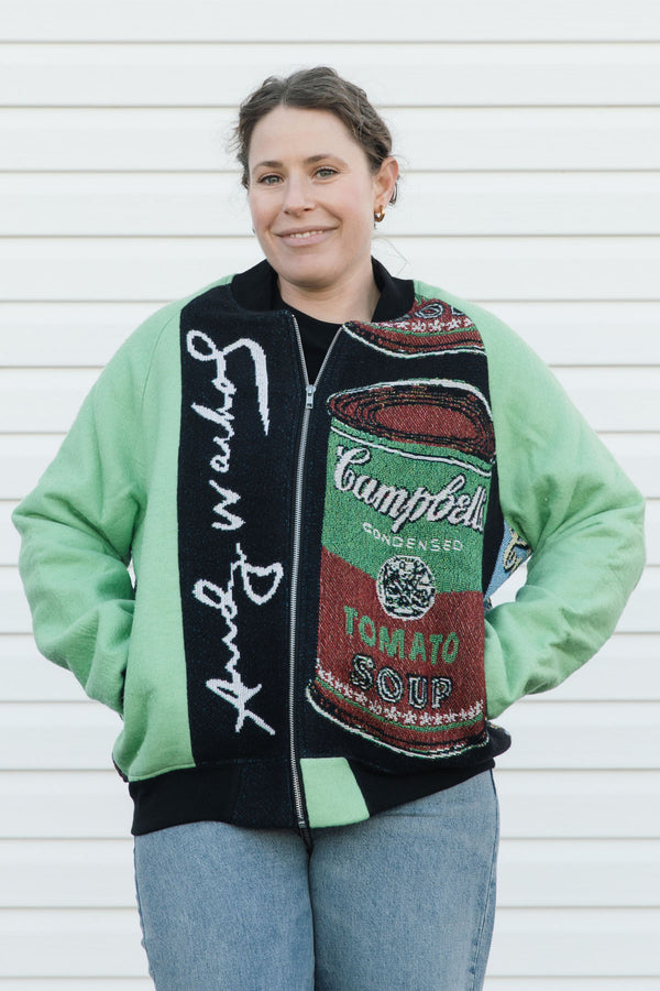 Person wearing a jacket with Campbell's Tomato Soup design against a white wall