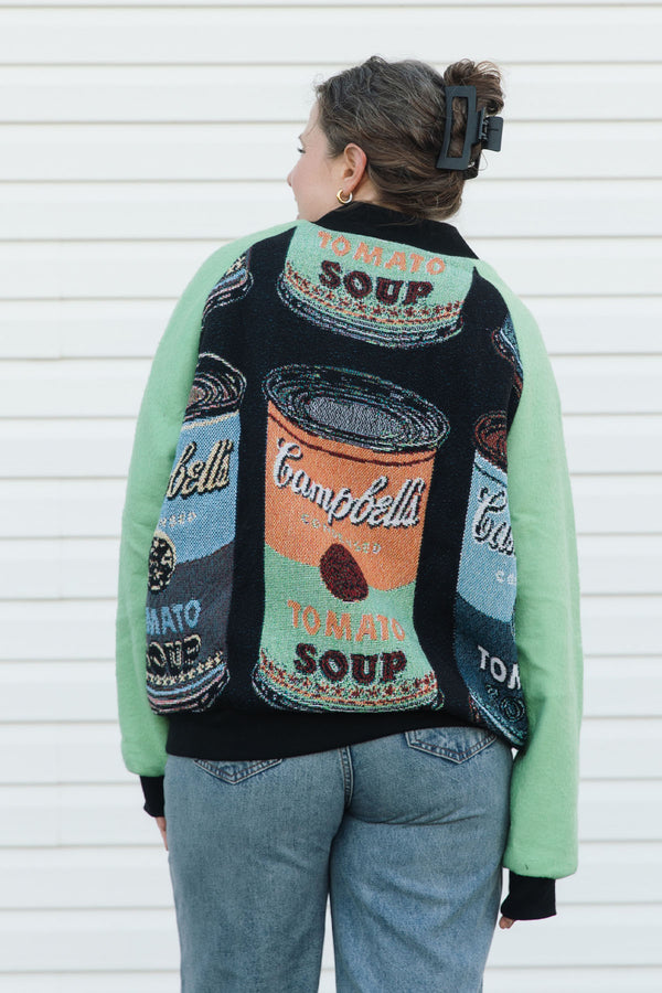 Person wearing a colorful Campbells Soup themed sweater against a white background