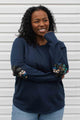 woman wearing a casual bamboo cotton sweater with floral elbow patches