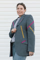 Woman wearing a gray blazer with pink and yellow accents against a white background