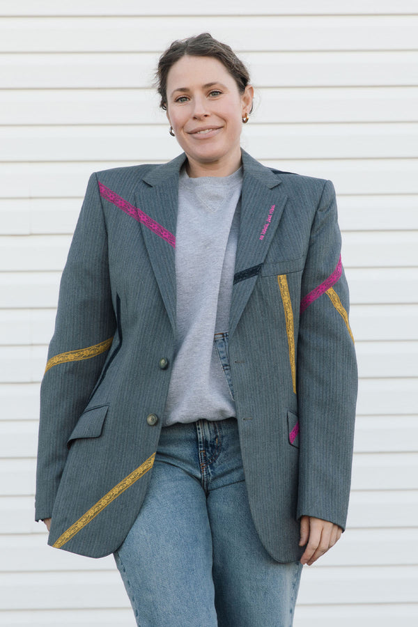Person wearing a gray blazer with colorful accents against a white background