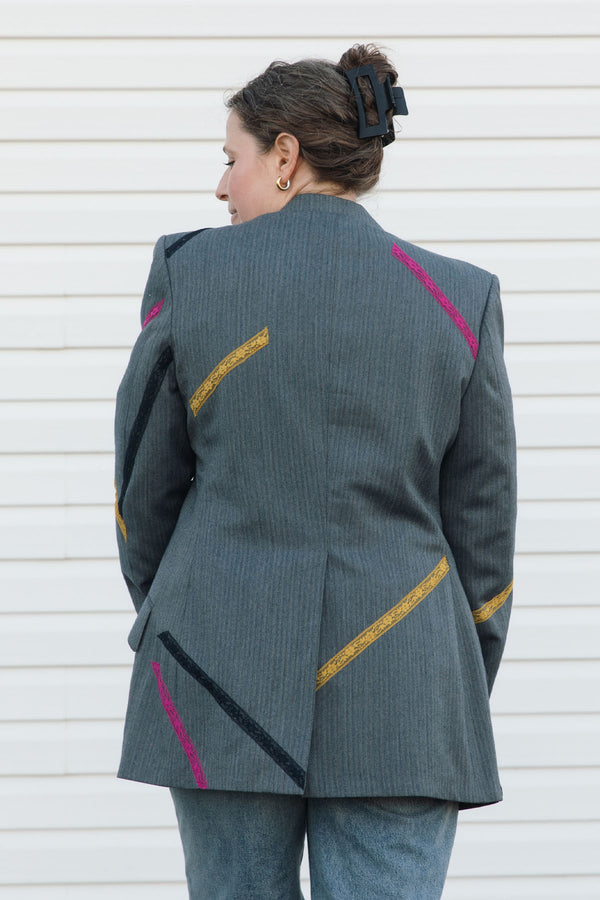 Person wearing a gray blazer with colorful accents against a white background