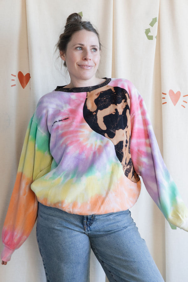 Person wearing a colourful tie-dye sweatshirt with a black bleached design, upcycled in canada