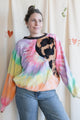 Person wearing a colourful tie-dye sweatshirt with a black bleached design, upcycled in canada