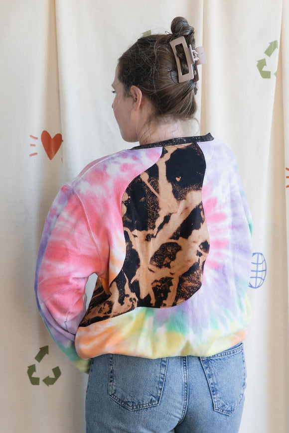 Person wearing a colourful tie-dye sweatshirt with a black bleached design, upcycled in canada