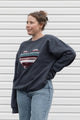 Woman wearing a dark gray sweatshirt with a colorful heart design sewn in canada