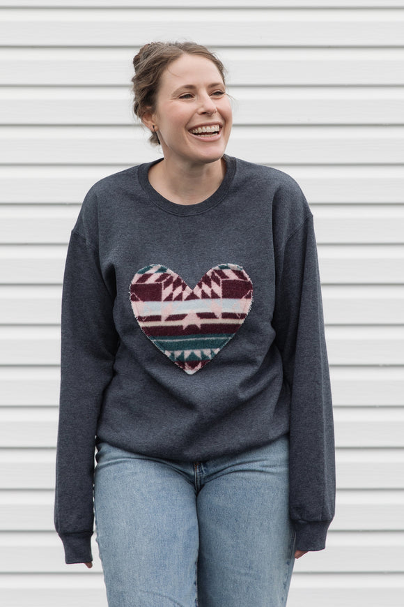 Woman wearing a dark gray sweatshirt with a colorful heart design sewn in canada