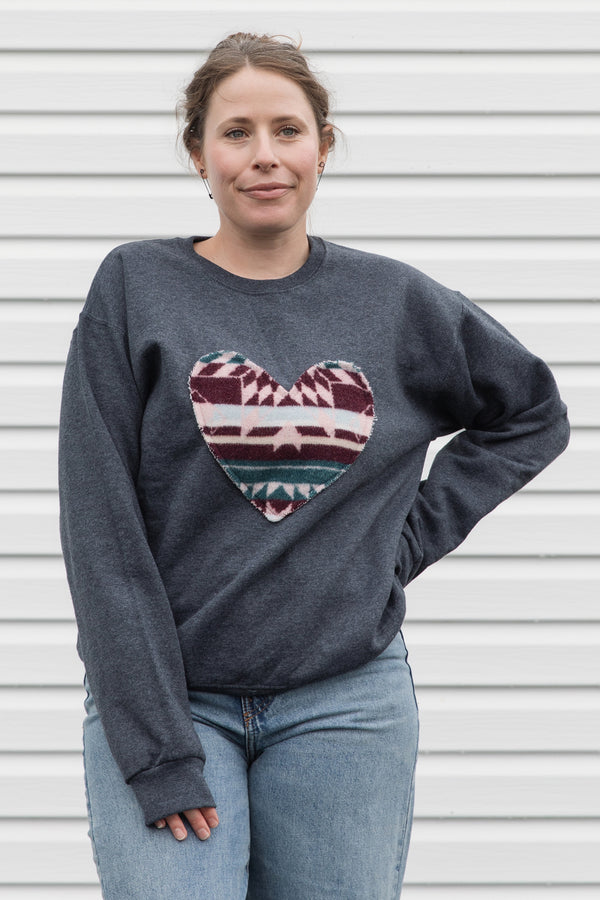 Woman wearing a dark gray sweatshirt with a colorful heart design sewn in canada