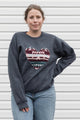 Woman wearing a dark gray sweatshirt with a colorful heart design sewn in canada