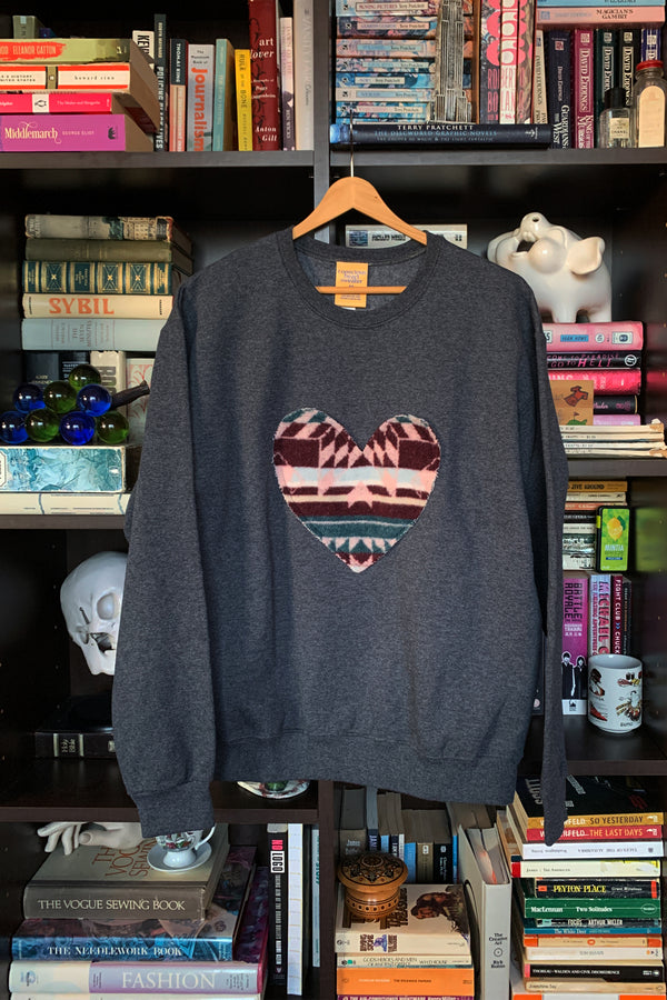 Woman wearing a dark gray sweatshirt with a colorful heart design sewn in canada