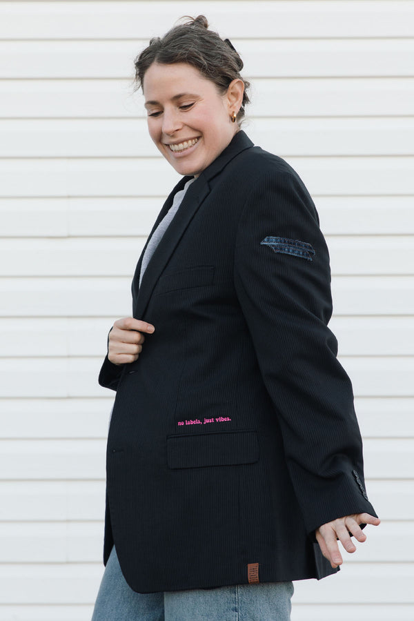 Person wearing a black blazer with text on the sleeve against a white background