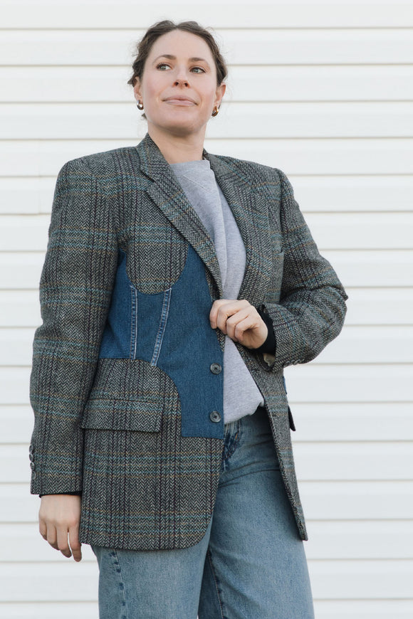 Person wearing a gray blazer with blue accents against a white background