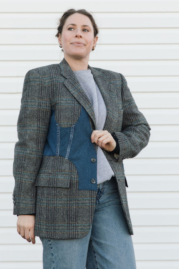 Person wearing a gray blazer with blue accents against a white background