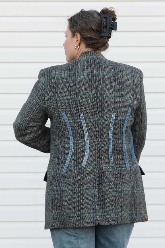 Person wearing a gray checkered blazer with blue accents against a white background