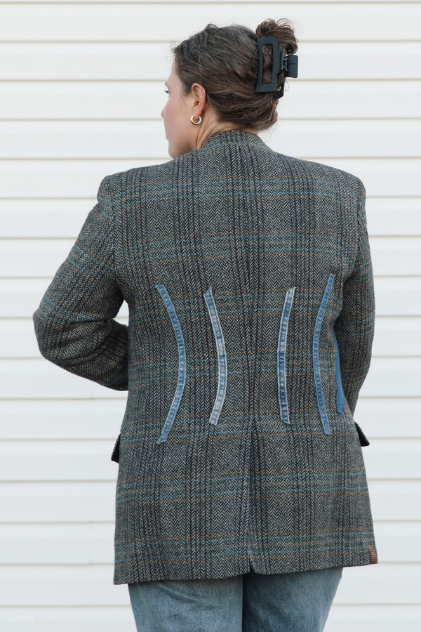 Person wearing a gray checkered blazer with blue accents against a white background