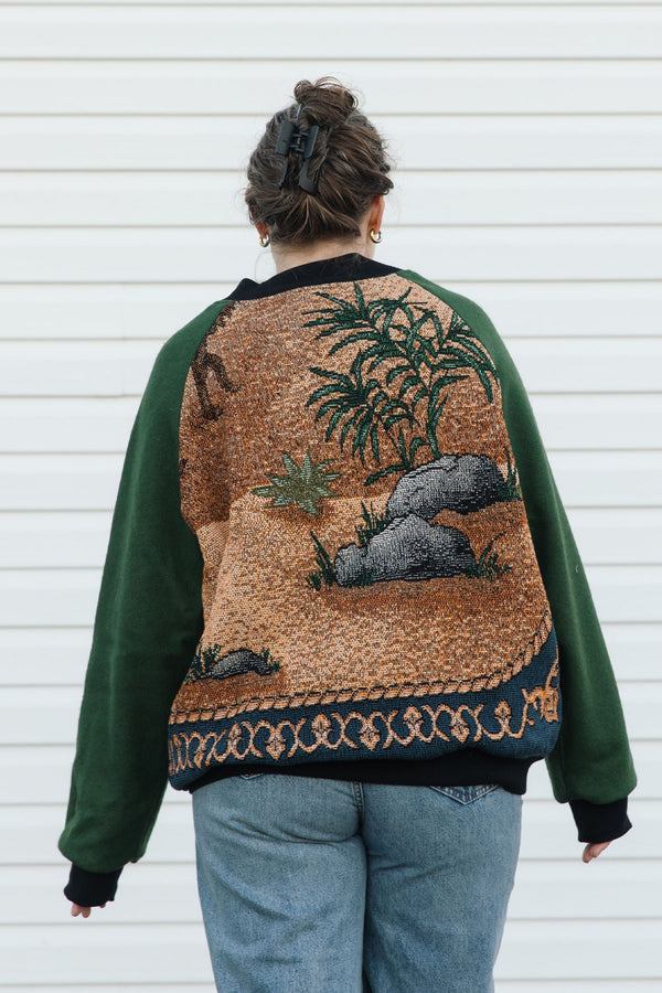 Person wearing a green and patterned jacket, featuring a starry night in the desert against a white background