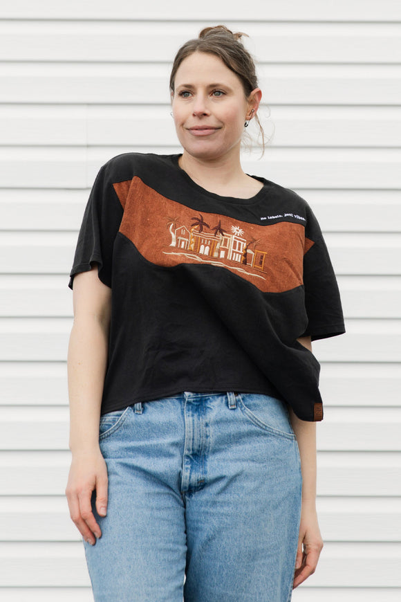 Woman wearing an upcycled black t-shirt with a brown graphic design against a white background