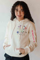 unisex cream hoodie with hand embroidered doodles, upcycled clothing, embroidered with no labels, just vibes on sleeve