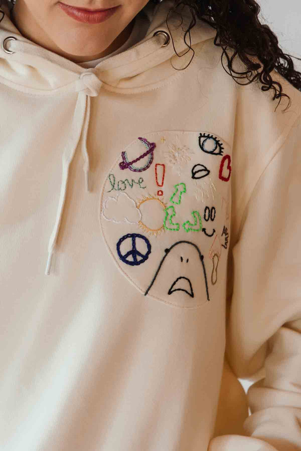 unisex cream hoodie with hand embroidered doodles, upcycled clothing, embroidered with no labels, just vibes on sleeve