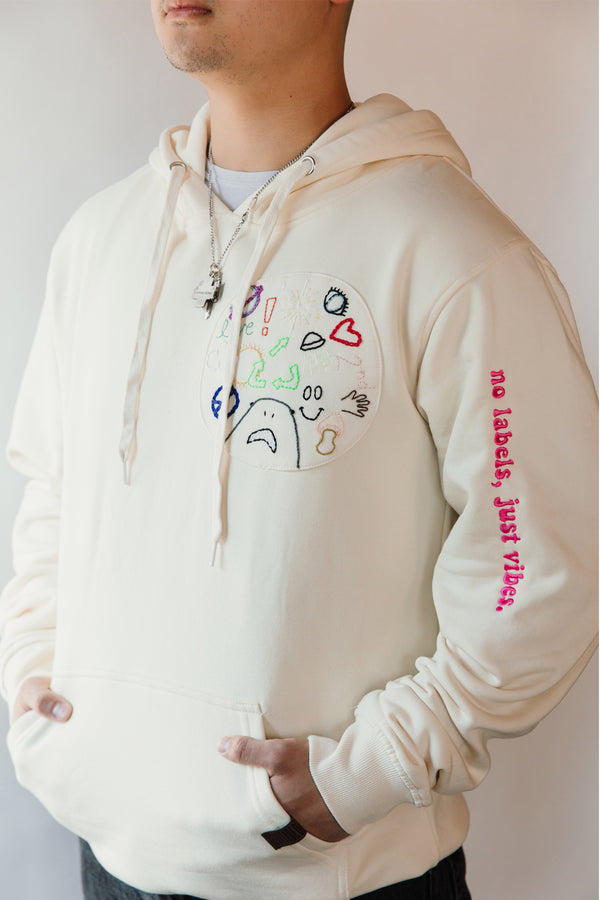 unisex cream hoodie with hand embroidered doodles, upcycled clothing, embroidered with no labels, just vibes on sleeve