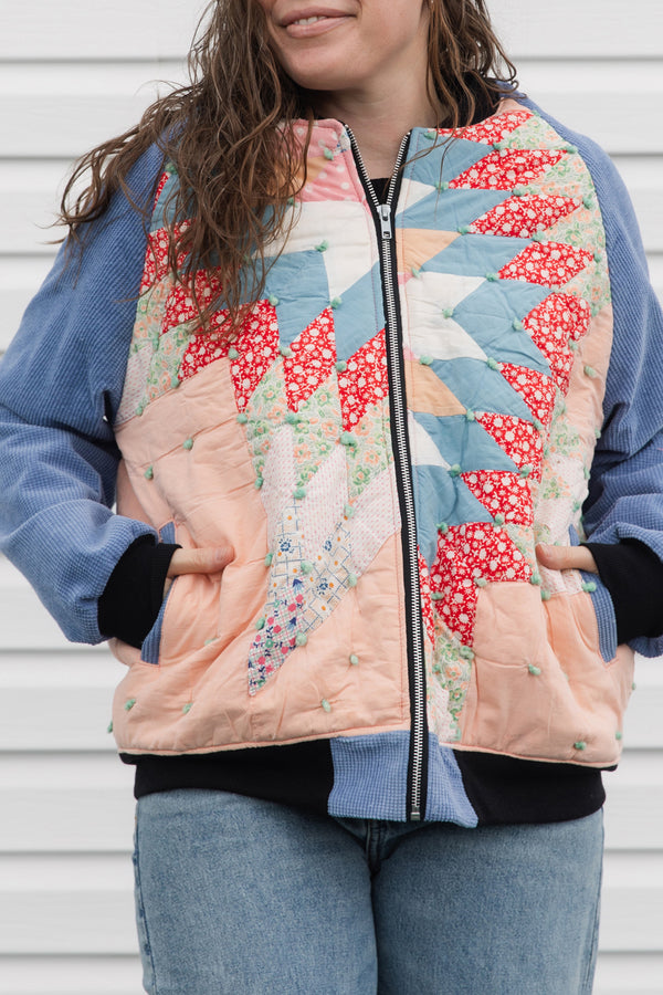 quilt turned bomber jacket, upcycled and repurposed. featuring red, peach, blues and greens with periwinkle sleeves. made in canada
